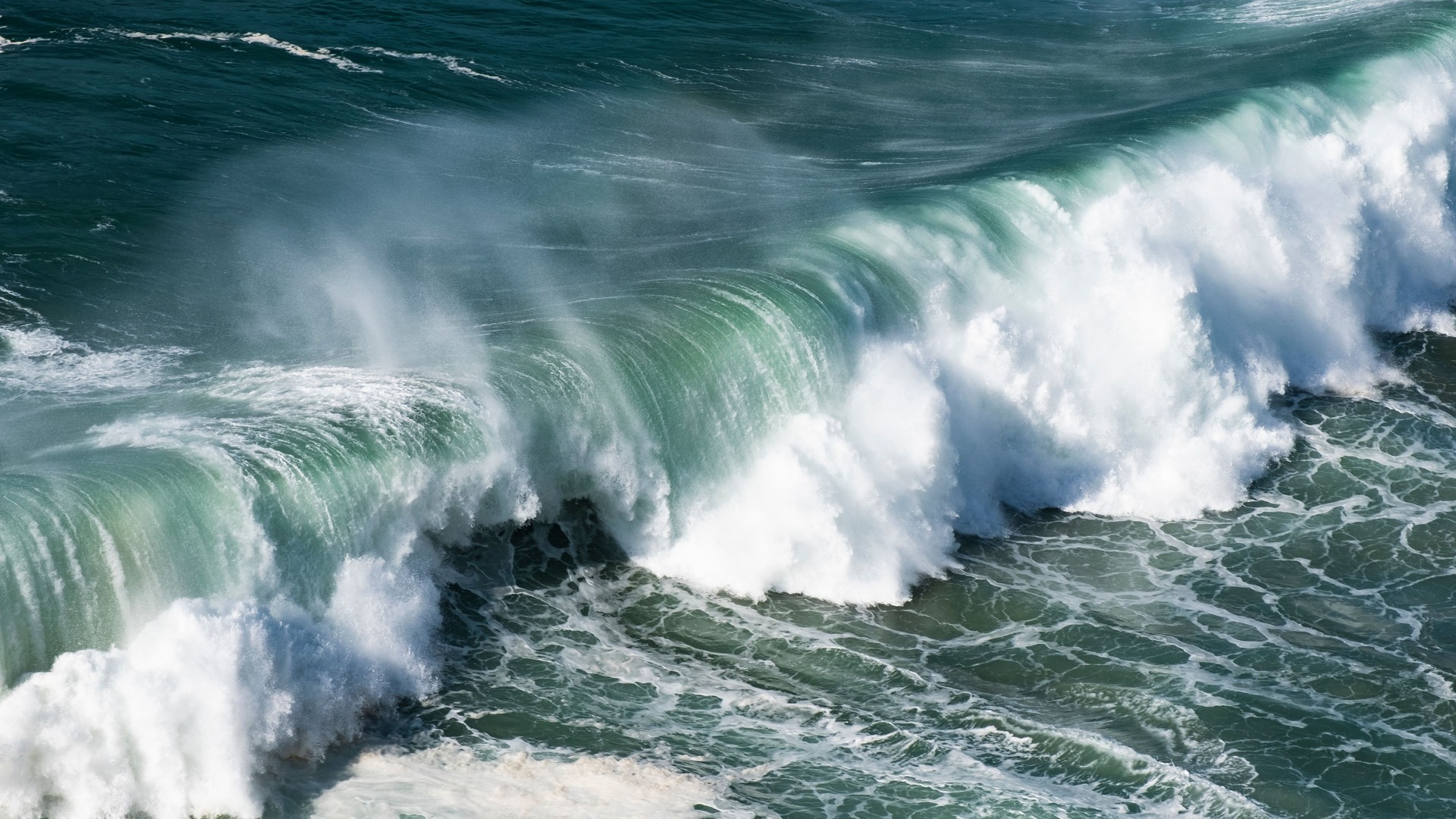 Giant ocean waves crash on the water surface forming a rainbow