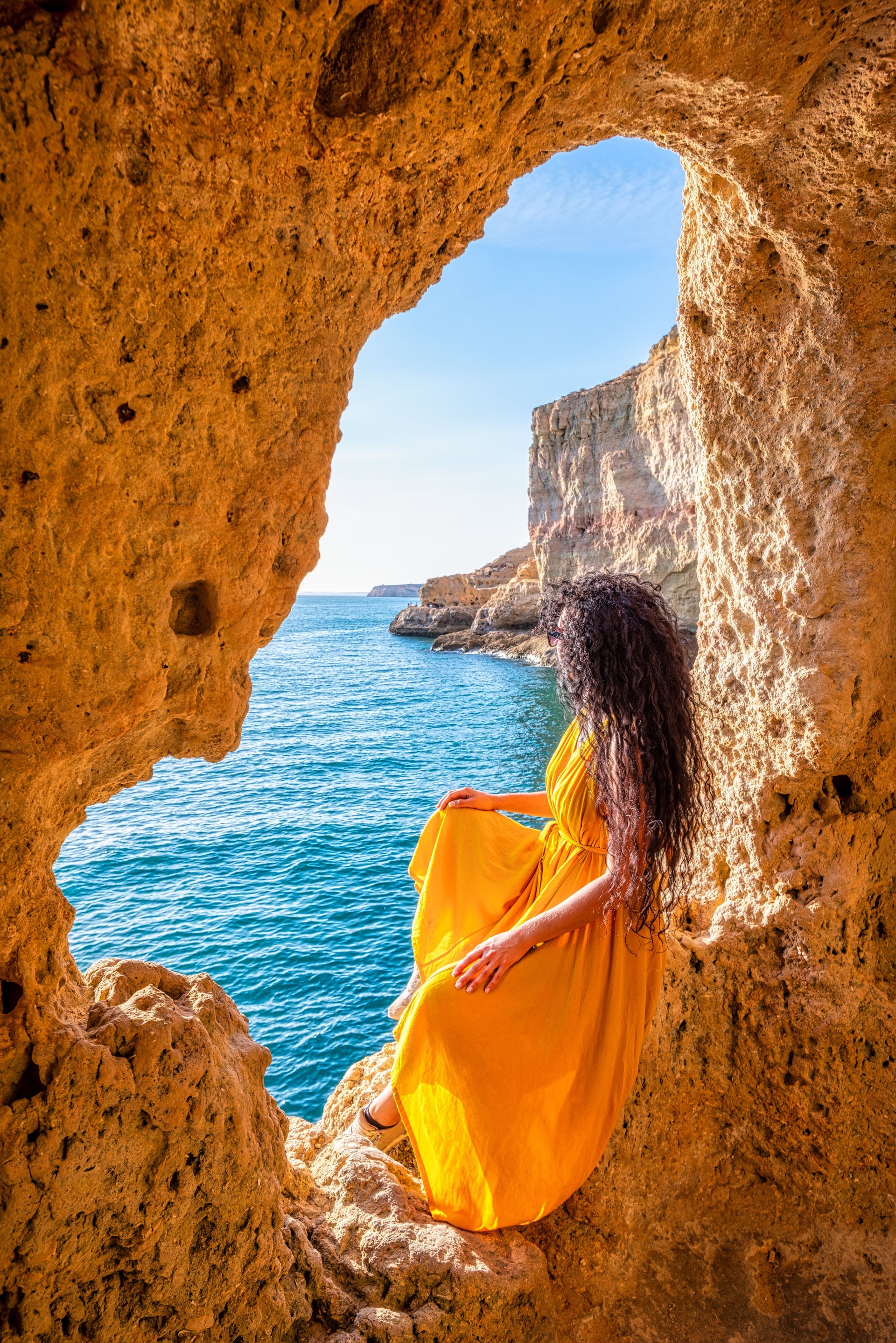 Woman in Yellow Dress Admiring Ocean View from Boneca cave in Algar Seco, Carvoeiro, Algarve, Portugal